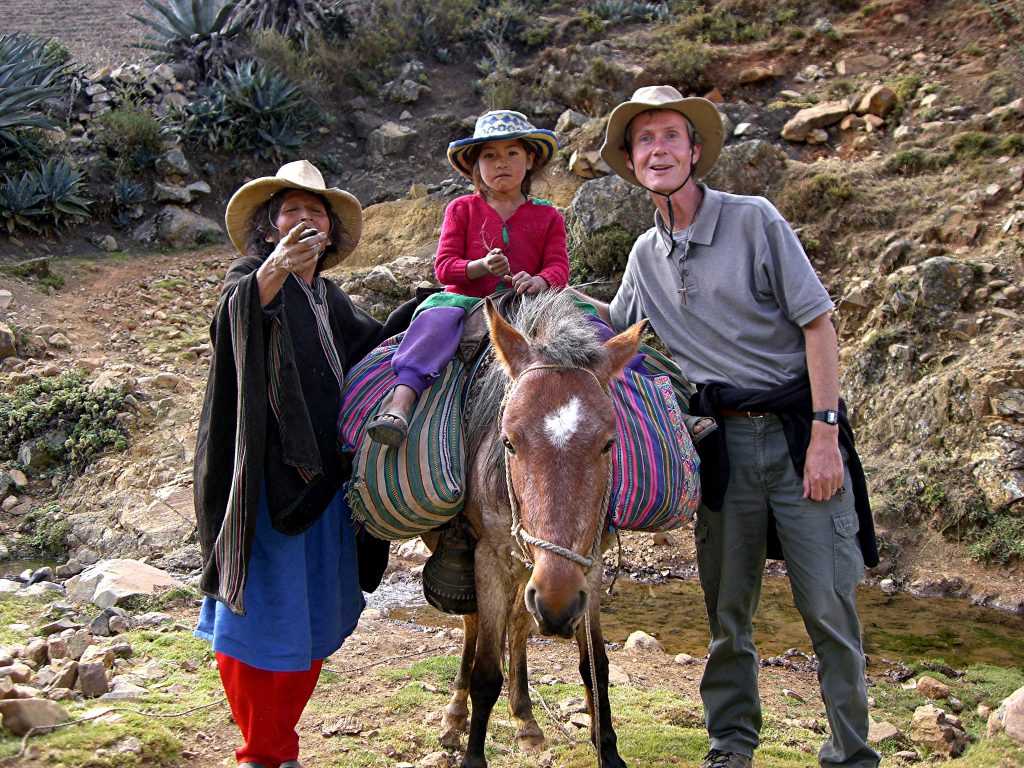Fr Kevin standing next to to Peruvians (one child on a mule and one adult next to him)